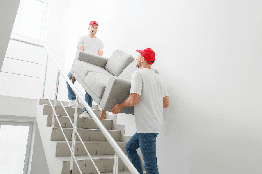 two men carrying a couch down stairs during a junk removal project